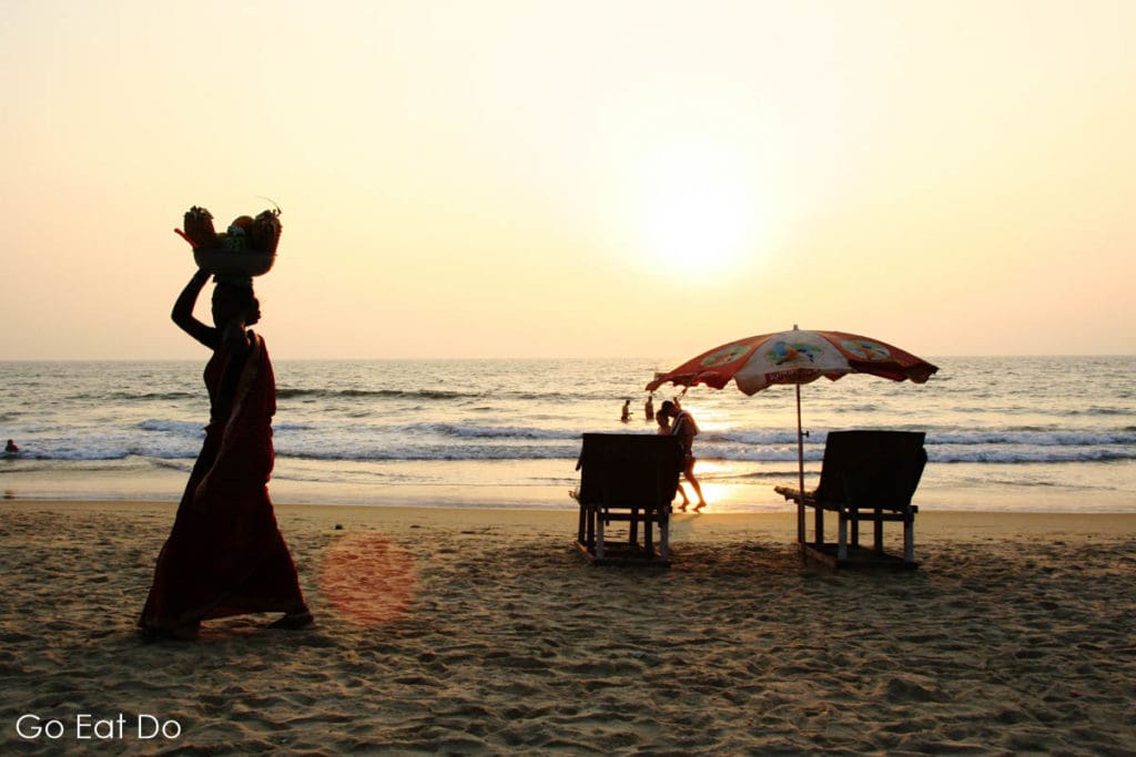 Silhouette of a woman walking on a beach in Goa, India.