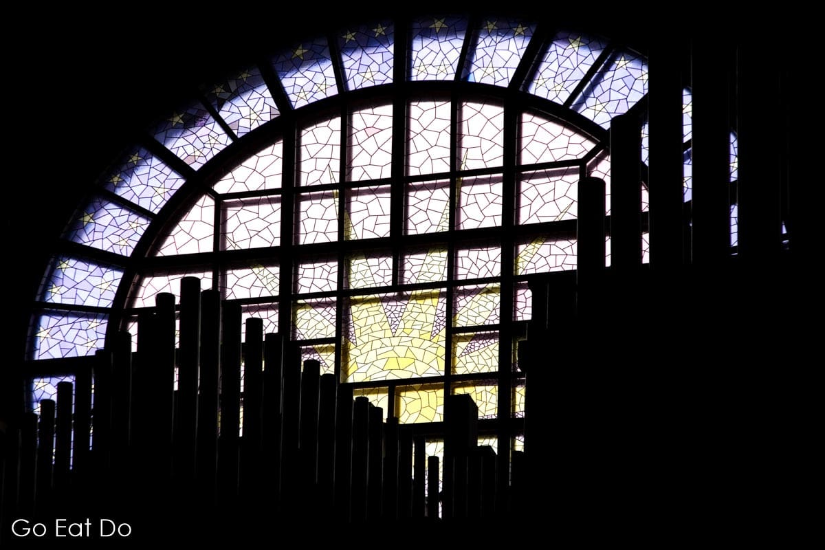 Pipe organ silhouetted by light flooding through the stained glass window in Tampere Cathedral.