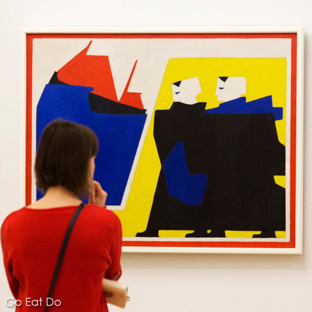 A visitor to the Kunstmuseum Den Haag views one of Bart van der Leck's artworks during the institution's 100 Years of De Stijl exhibition