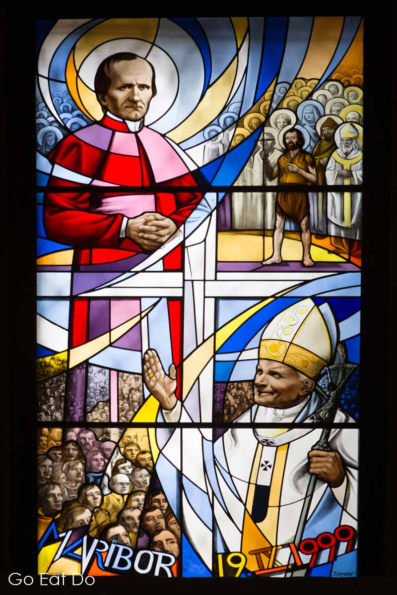 Stained glass depicting Bishop Anton Martin Slomšek looking more like Robin Williams and Pope John Paul II.