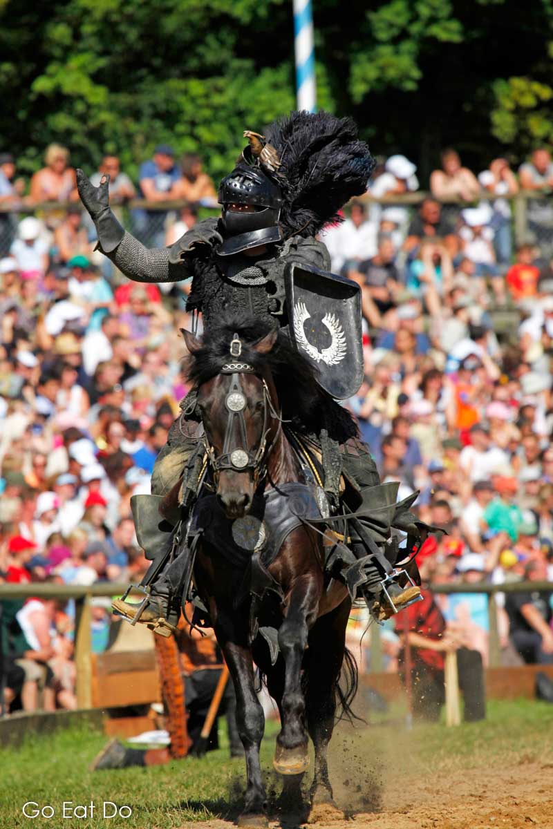 Knight in armour galloping in the arena at Kaltenberg Castle near Munich, Germany.