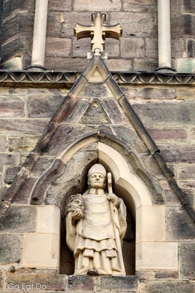 Statue of St Cuthbert holding a severed head above the entrance to the church.