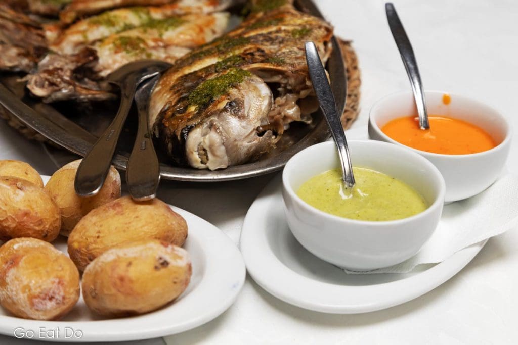 Traditional Canarian wrinkled potatoes, papas arrugadas, served with green and red mojo sauce and grilled fish at one of the best restaurants in Tenerife for food from the Canary Islands.