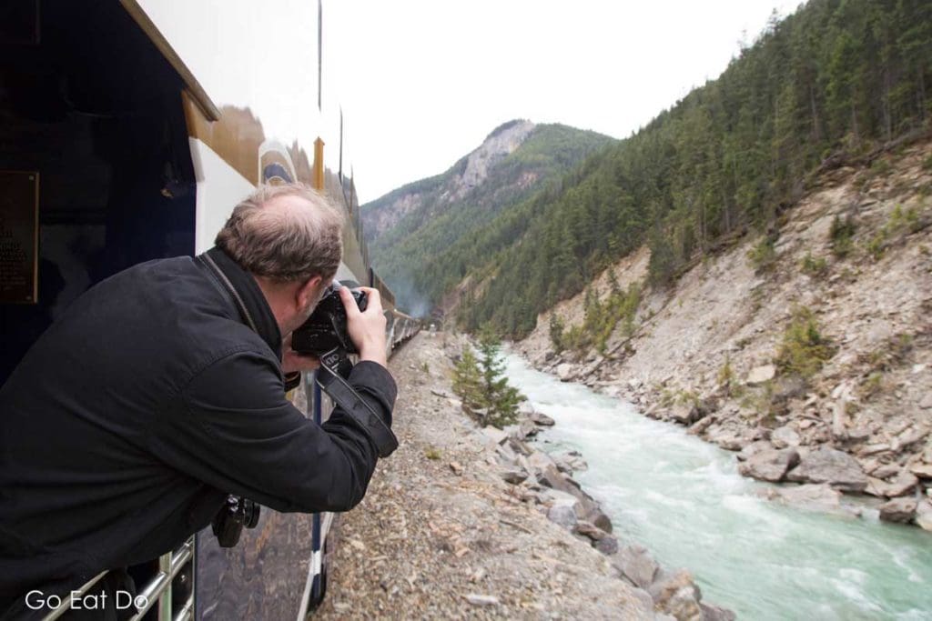 A man photographs mountainous landscape scenery in Alberta during the Rocky Mountaineer's First Passage to the West.