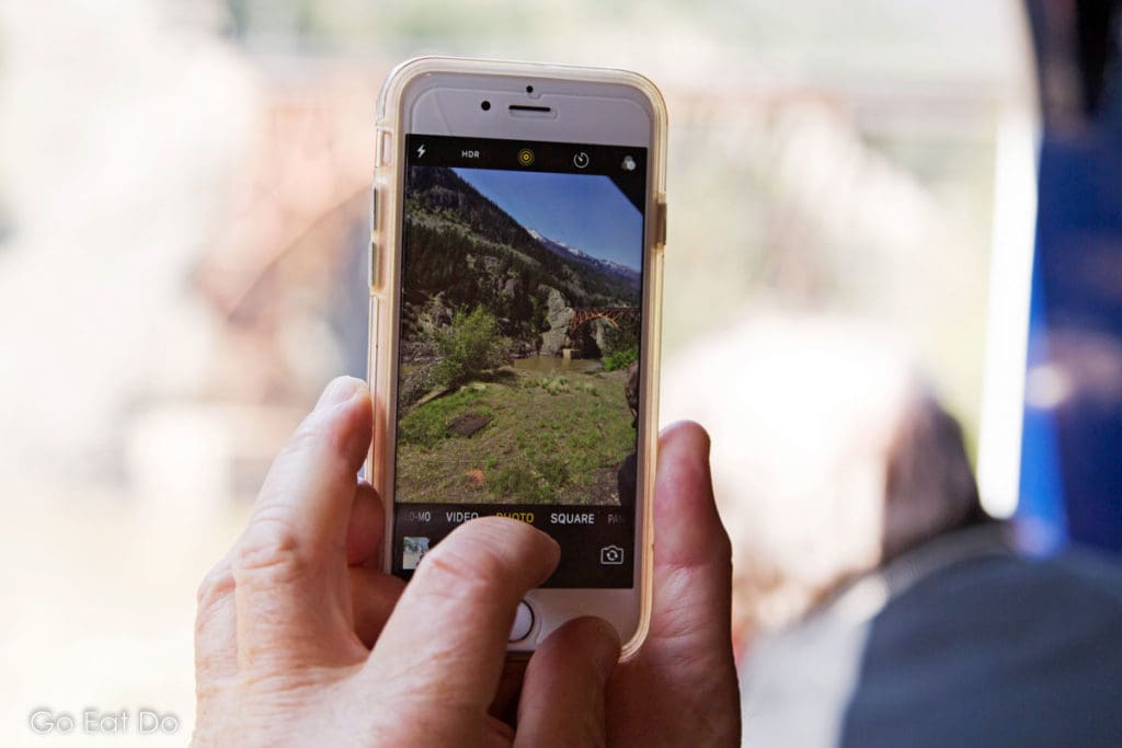 Smartphone photographing landscape in western Canada during a scenic train ride on the Rocky Mountaineer