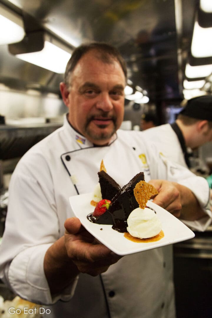 Executive chef shows a dessert prepared in the galley of a Rocky Mountaineer train