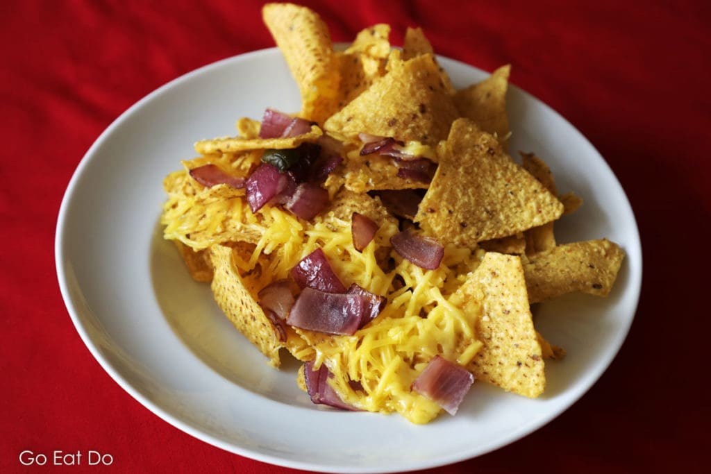 Vegan nachos prepared with Violife original flavour grated, red onion and sliced jalapeno pepper.