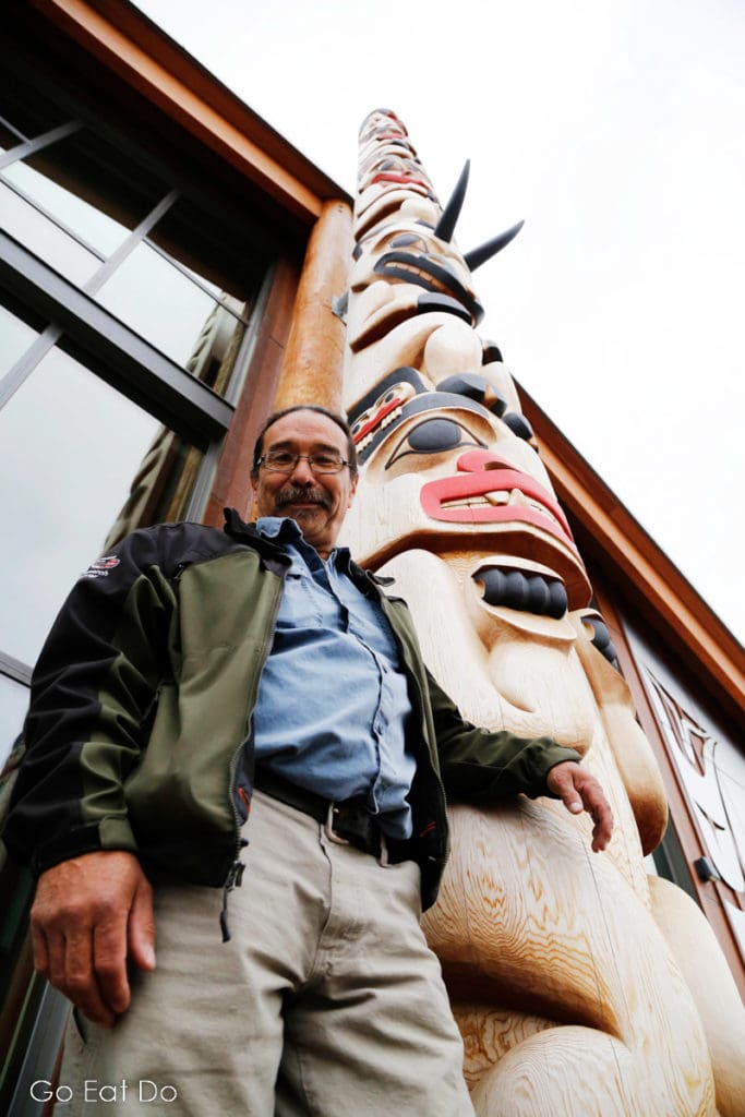 Keith Wolfe Smarch by one of the totem poles he has carved at Haa Shagóon Hídi in Carcross.