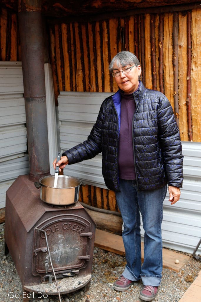 Meta Williams cooking on a stove at Kwäday Dän Kenji, the Long Ago Peoples Place, in Champagne, the Yukon.
