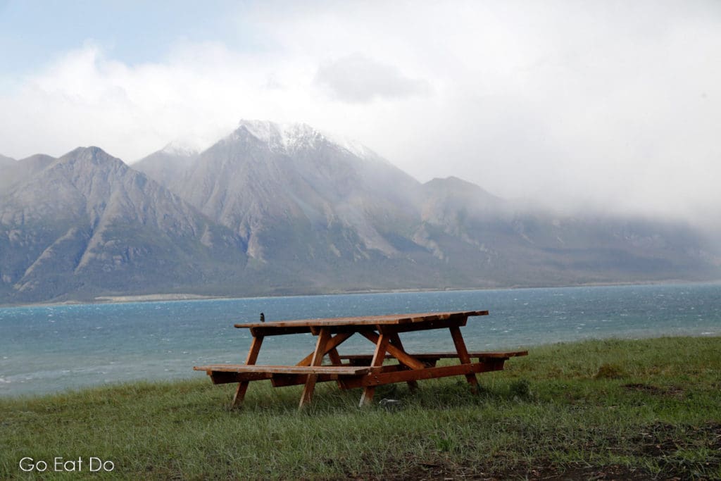 Picnic bench with a scenic view at Shakat Tun Wilderness Camp, where people can learn about the heritage of First Nations in Yukon, Canada.