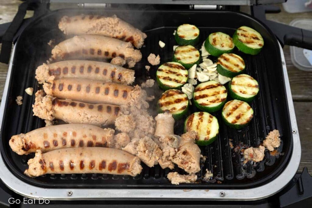 Homemade sausages and courgette grilling on a Ninja Woodfire Electric BBQ Grill and Smoker.