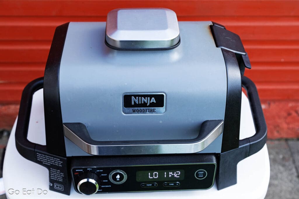 A Ninja Woodfire Electric BBQ Grill and Smoker being used outdoors.